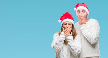 Orta yaş İspanyol çift üzerinde Noel şapka arka plan ağız hata için elleriyle kapsayan şok izole. Gizli kavramı.