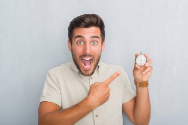Kronometre çok mutlu el ve parmak ile işaret tutan gri grunge duvarın üzerinden yakışıklı genç