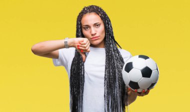 Kızgın yüz, eksi işareti aşağı antipati başparmak ile gösterilen, ret kavramı ile izole arka plan üzerinde futbol topu tutan genç örgülü saç Afro-Amerikan Kız