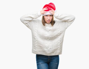 Çünkü çaresiz ve stresli baş ağrısı acı izole arka plan üzerinde Noel şapka giyen genç güzel beyaz kadın ağrı ve migren. Ellerini kafasına.