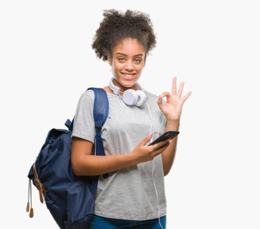 Sırt çantası parmak, mükemmel sembolü ile ok işareti yapıyor izole arka plan üzerinde tutan genç güzel afro Amerikan öğrenci kadın