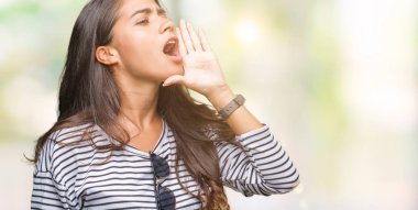 Genç güzel Arap kadın bağırarak ve ağzı üzerinde el ile yan için çığlık izole arka plan üzerinde güneş gözlüğü takıyor. İletişim kavramı.