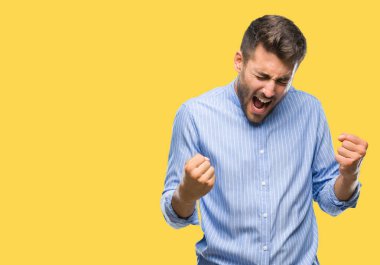 Soyutlanmış, mutlu ve heyecanlı genç bir adam kollarını kaldırmış, gülümseyen ve başarı için çığlık atan kazanan bir jest yapıyor. Kutlama konsepti.