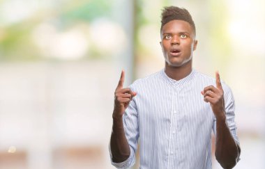 Genç Afro-Amerikan adam izole arka plan üzerinden hayran ve yukarıya bakıp parmakları ile işaret şaşırttı ve silah kaldırdı.