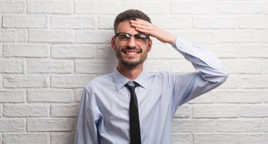 Genç Yetişkin iş adam kafasına, utanç ve sürpriz yüz ile şok el ile vurguladı beyaz tuğla duvarın üzerinden ayakta öfkeli ve sinirli. Korku ve hata için üzgün.