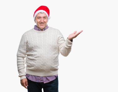 Üst düzey yakışıklı Noel şapka neşeli sunulması ve kameraya bakarak avucunun ile işaret gülümseyen izole arka plan üzerinde.