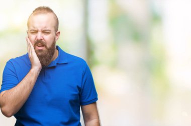 Diş ağrısı veya dişlerde dişlerle ilgili hastalık nedeniyle ağız acı ifadesi ile el ile dokunmak izole arka plan üzerinde mavi gömlek giymiş genç beyaz hipster adam. Diş hekimi kavramı.