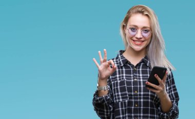 Sarışın genç kadın texting parmak, mükemmel sembolü ile ok işareti yapıyor izole arka plan üzerinde Smartphone kullanarak ileti gönderme