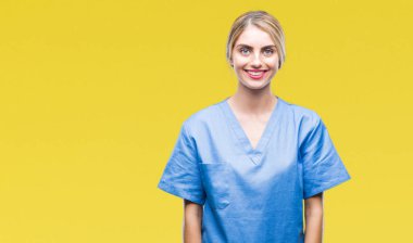 Genç güzel sarışın doktor cerrah hemşire kadın yüzünde mutlu ve güzel bir gülümseme ile izole arka plan yüzünden. Şanslı kişi.