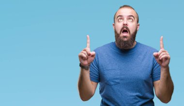 Genç beyaz hipster adam izole arka plan üzerinden hayran ve yukarıya bakıp parmakları ile işaret şaşırttı ve silah kaldırdı.