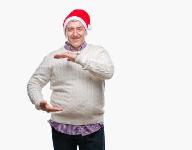 İzole arka plan eller eller büyük gösterilen ve büyük boy işareti, ölçü birimi sembolü ile üzerinde Noel şapka giymiş yakışıklı komuta sizde. Kameraya bakarak gülümsüyordu. Ölçüm kavramı.
