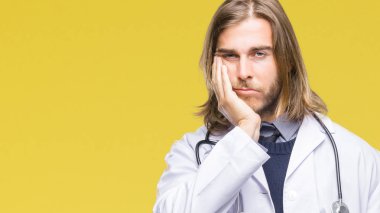 Genç yakışıklı Doktor adam uzun saçlı izole arka plan düşünme seyir üzerinde yorgun ve sıkılmış çapraz silah depresyon sorunları ile.