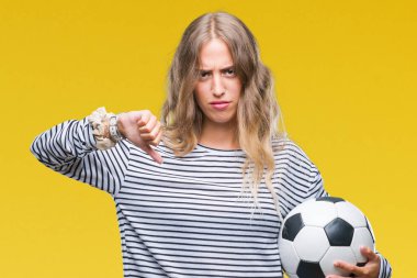 Kızgın yüz, eksi işareti aşağı antipati başparmak ile gösterilen, ret kavramı ile izole arka plan üzerinde futbol futbol topu tutan genç güzel sarışın kadın