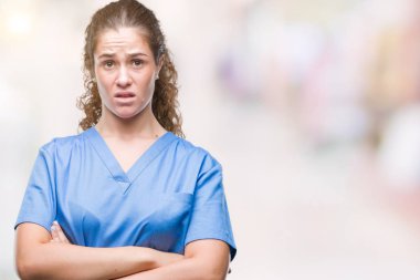 Hemşire veya çapraz kolları olan yüzündeki ifade onaylamayan cerrah izole arka plan şüpheci üzerinde üniforma ve sinir, giyen genç esmer doktor kız. Negatif kişi.