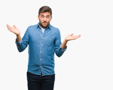 İzole arka plan clueless ve şaşkın bir ifadeyle kollar ve eller kaldırdı genç yakışıklı adam. Şüphe kavramı.