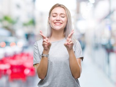 Genç Sarışın kadın geçiş parmakları umut ve gözler gülümseyen izole arka plan yüzünden kapalı. Şans ve batıl kavramı.