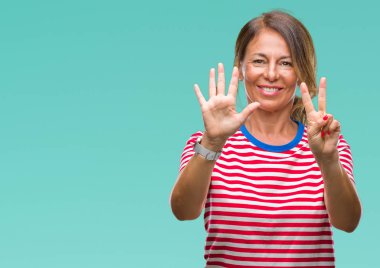 Orta yaş üst düzey İspanyol kadın gösterilen ve parmakları ile işaret izole arka plan yüzünden kendinden emin ve mutlu gülümseyerek süre yedi numara.