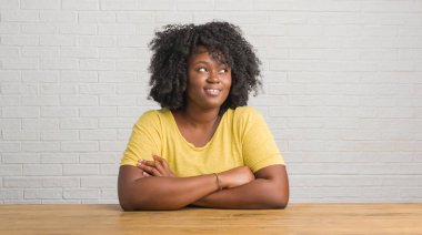 Gülümseyen masanın üzerinde evde genç Afro-Amerikan kadın görünümlü yan ve dik dik bakma uzağa düşünce.