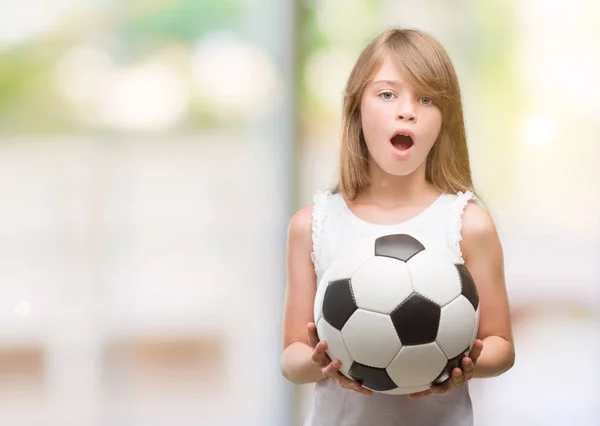 Młoda Blondynka Malucha Trzymając Piłki Nożnej Przestraszony Szoku Ścianą Niespodzianka — Zdjęcie stockowe