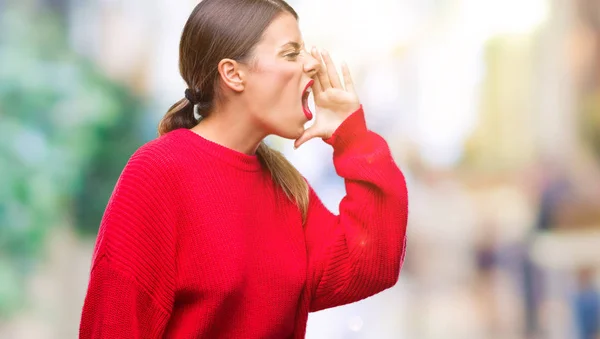 若い美しいビジネス女性が叫ぶと 口の中に手の側に大声で叫んで分離の背景に冬のセーターを着ています 通信の概念 — ストック写真