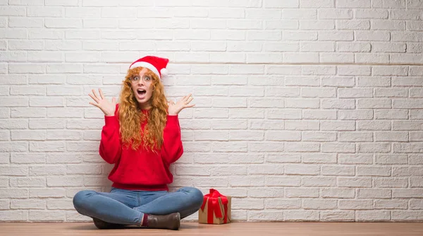 Young Redhead Woman Sitting Brick Wall Wearing Christmas Hat Celebrating — Stock Photo, Image