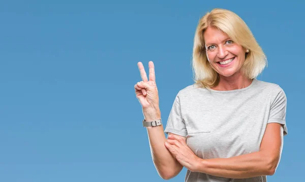Middle age blonde woman over isolated background smiling with happy face winking at the camera doing victory sign. Number two.