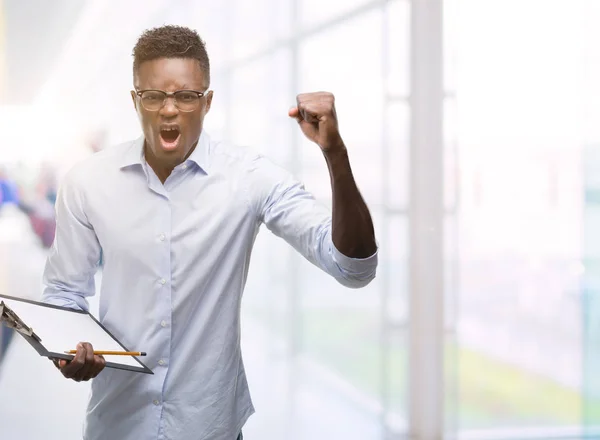 Joven Hombre Afroamericano Sosteniendo Clipboarad Molesto Frustrado Gritando Con Ira —  Fotos de Stock