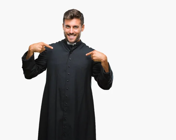 年轻的天主教基督教牧师男子在孤立的背景下 脸上露出自信的笑容 指着自己的手指骄傲和快乐 — 图库照片