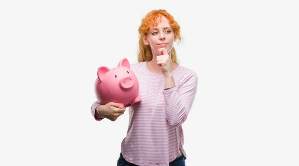 Jonge Roodharige Vrouw Met Spaarvarken Ernstige Gezicht Denken Vraag Zeer — Stockfoto