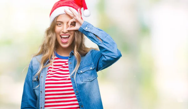 手の笑顔 幸せそうな顔で指を通して見る目で のジェスチャーを行う分離の背景にクリスマス帽子身に着けている美しい若いブロンドの女性 — ストック写真