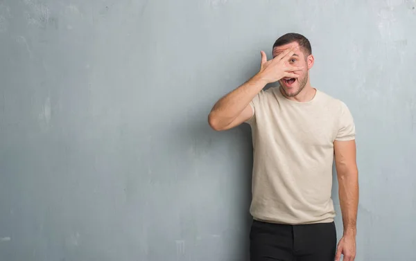 Joven Hombre Caucásico Sobre Gris Pared Grunge Asomándose Shock Cubriendo — Foto de Stock