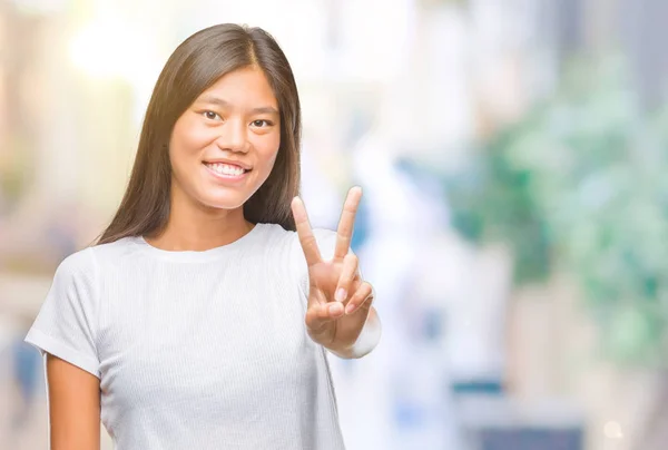 在孤独的背景下 年轻的亚洲妇女微笑着快乐的脸眨眼在相机做胜利标志 第二个 — 图库照片