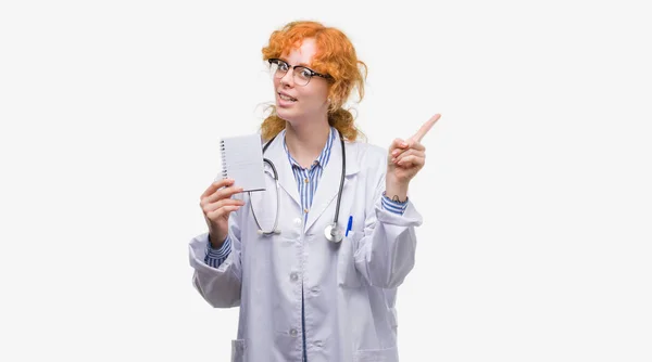 Jovem Ruiva Médico Mulher Segurando Notebook Branco Muito Feliz Apontando — Fotografia de Stock