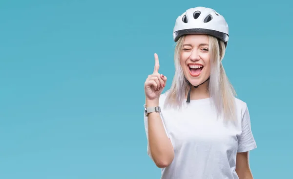 年轻的金发女郎穿着自行车安全头盔在孤立的背景下 指着成功的想法 退出和快乐 第一个 — 图库照片