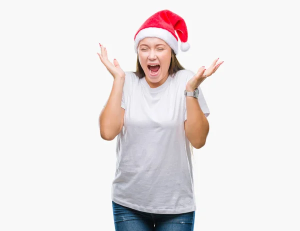 若い美しい白人女性にクリスマスの帽子をかぶって狂気を祝う背景を分離した腕を上げると成功のためびっくりし 叫んで興奮して目を開きます 勝者の概念 — ストック写真