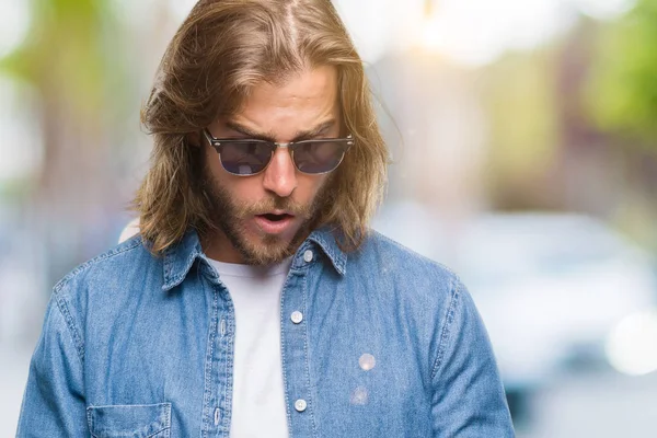 Bir sürpriz yüz, korkuyor ve heyecanlı korku ifadesi ile smartphone şokta korktuğunu kullanarak ileti gönderme izole arka plan üzerinde uzun saçlı yakışıklı delikanlı