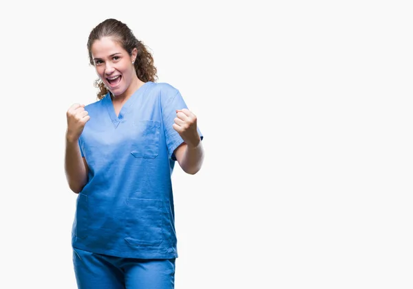 年轻的黑发医生女孩穿着护士或外科医生制服在孤立的背景非常高兴和兴奋做优胜者姿态与胳膊举起 微笑和尖叫为成功 庆祝理念 — 图库照片