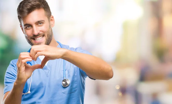 年轻英俊的医生外科医生人在孤独的背景微笑的爱显示心脏符号和形状与手 浪漫概念 — 图库照片