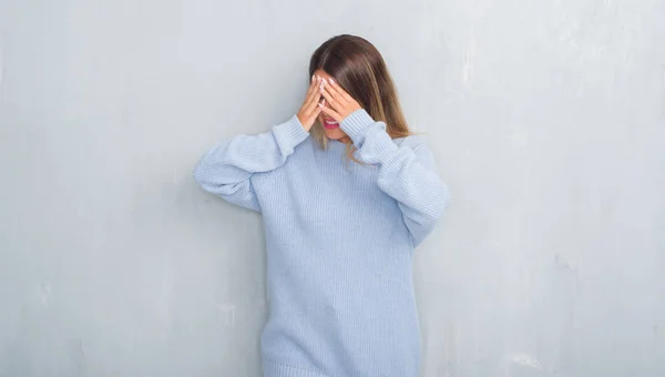 泣きながら手で顔を覆っている悲しそうな表情で冬の服装を着ているグレーのグランジの壁を越えて若い大人の女性 うつ病の概念 — ストック写真