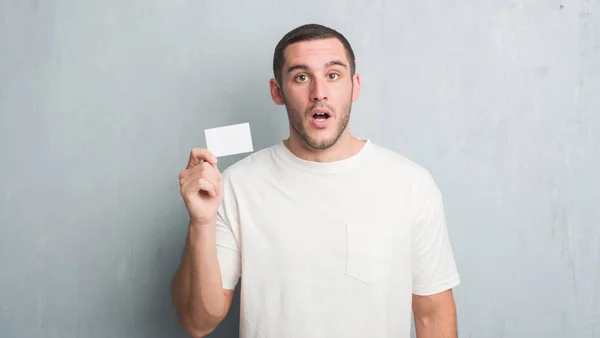 Joven Caucásico Hombre Sobre Gris Grunge Pared Mostrando Blanco Tarjeta — Foto de Stock