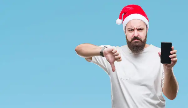 クリスマス帽子を示すスマート フォン画面上身に着けて若い白人男分離怒った顔 ダウン親指で嫌悪感を示すマイナス記号 拒絶反応の概念と背景 — ストック写真