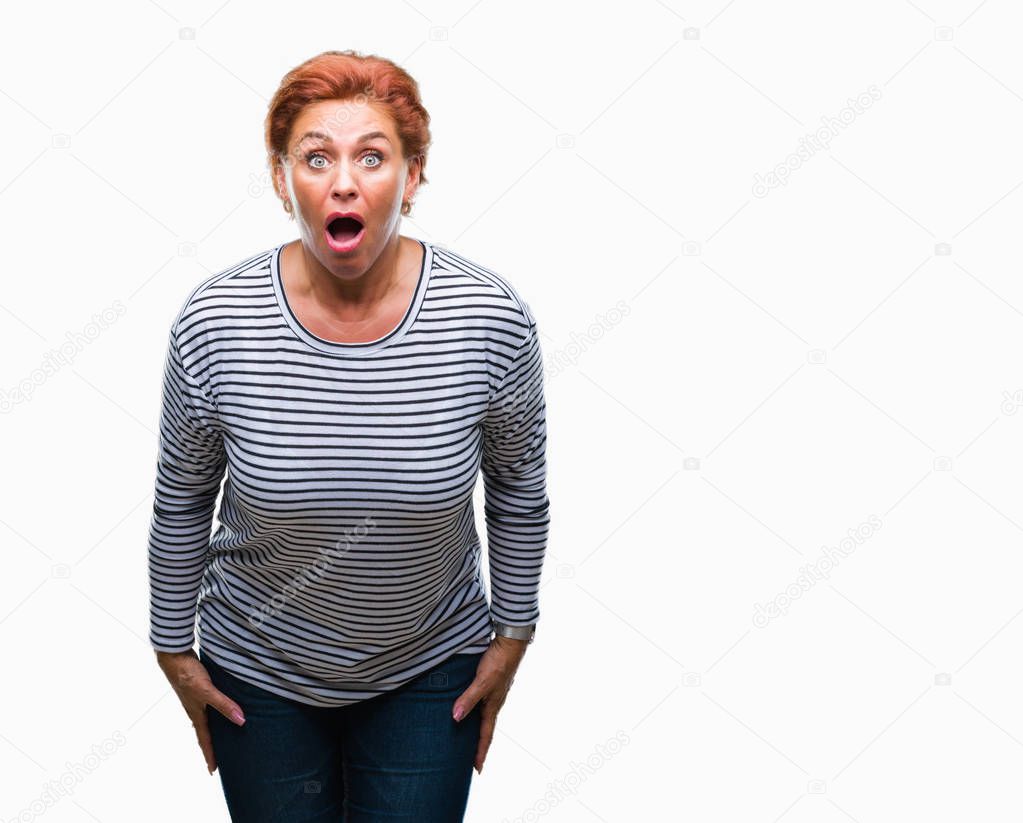 Atrractive senior caucasian redhead woman over isolated background afraid and shocked with surprise expression, fear and excited face.