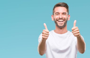 Yakışıklı delikanlı izole arka plan başarı işareti el ile pozitif jest yapıyor üzerinde başparmak gülümseyen ve mutlu. Neşeli bir ifadeyle, kazanan jest kameraya bakıyor.