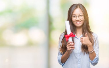 İzole arka plan üzerinde derecesi büyük gülümseme ok işareti, başparmak ile parmak, mükemmel işareti yapıyor ile mutlu tutan Genç Asyalı kadın