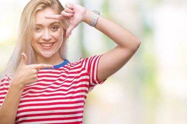 Genç Sarışın kadın elle yapma çerçeve ve parmakları ile mutlu yüz gülümseyen izole arka plan yüzünden. Yaratıcılık ve Fotoğrafçılık kavramı.