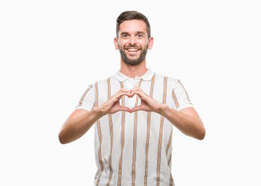 Yakışıklı delikanlı aşık kalp simgesi ve elleriyle şekil gösteren gülümseyen izole arka plan üzerinde. Romantik kavramı.