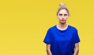 Çatık izole arka plan şüpheci ve gergin, mavi t-shirt giyen genç güzel sarışın ve mavi gözlü kadın sorunu nedeniyle üzgün. Negatif kişi.