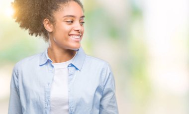 Uzak tarafına yüzünde, doğal ifade gülümseme ile seyir izole arka plan üzerinde genç afro Amerikalı kadın. Kendine güvenen gülüyor.