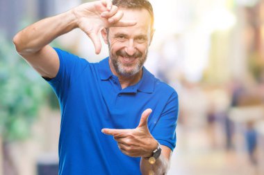 Orta yaş elle yapma çerçeve ve parmakları ile mutlu yüz gülümseyen izole arka plan üzerinde ağarmış komuta sizde. Yaratıcılık ve Fotoğrafçılık kavramı.