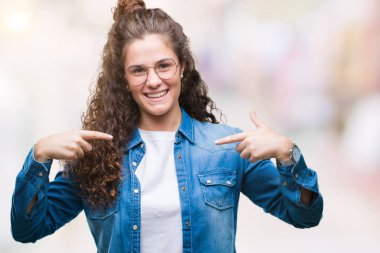 Yüzünde gülümseme ile kendinden emin görünüyorsun, kendini gururlu ve mutlu parmakları ile işaret izole arka plan üzerinde gözlük güzel genç esmer kıvırcık saçlı kız.